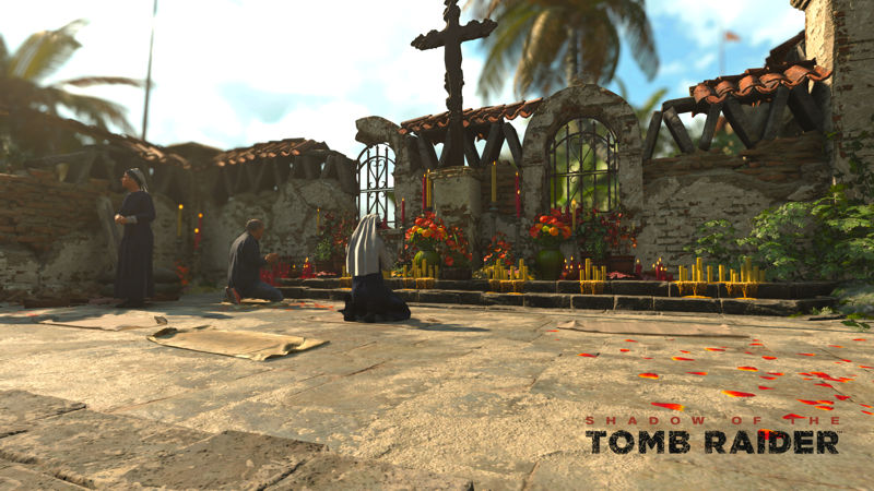 Image shows people knelt and praying at a cross in an open courtyard.